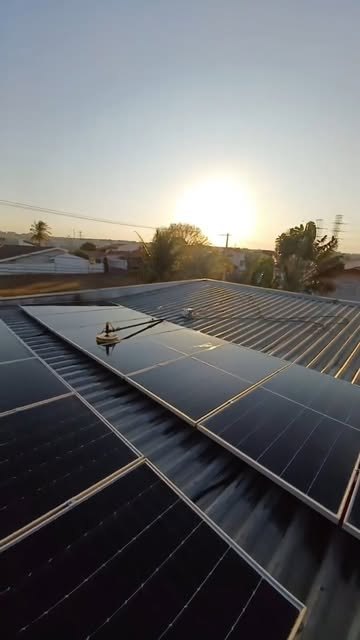 Placas solares instaladas em telhado metálico ao pôr do sol